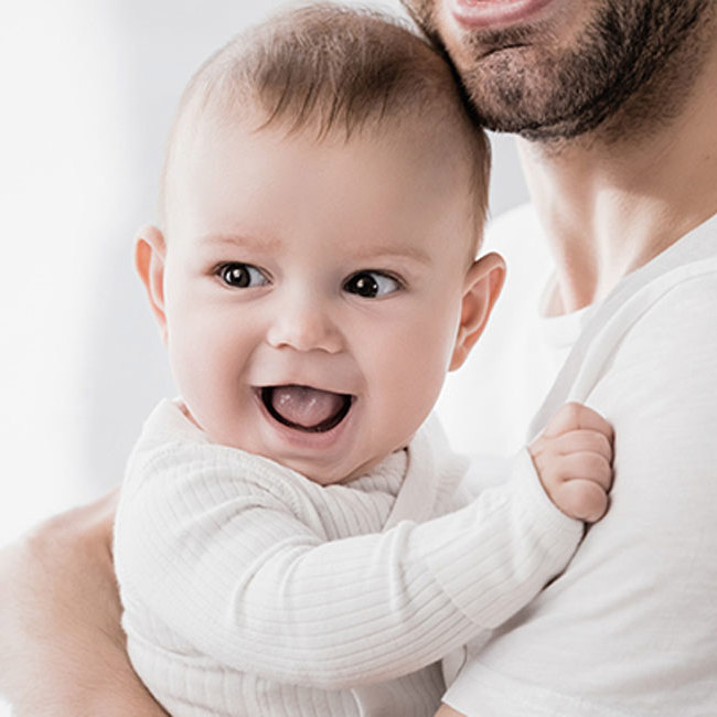 En smilende baby i armene på sin far.