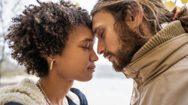 En ung kvinde og mand står med hovederne tæt sammen.